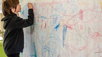 Kind dat creatief bezig is met tekenen op de muur