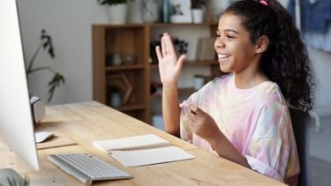 lessen / meisje zwaait naar webcam op computer