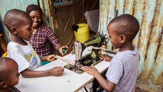 opvoedgewoontes / Keniaans gezin zit om naaimachine heen
