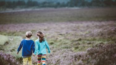 Een jongen en een meisje die hand in hand lopen omdat een ouder zijn zoon feministisch heeft opgevoed