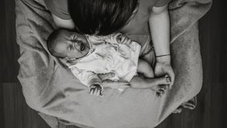 baby huilt na voeding Moeder met huilende baby op haar schoot