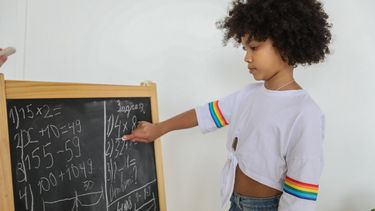 tafels leren / kind rekent op een schoolbord